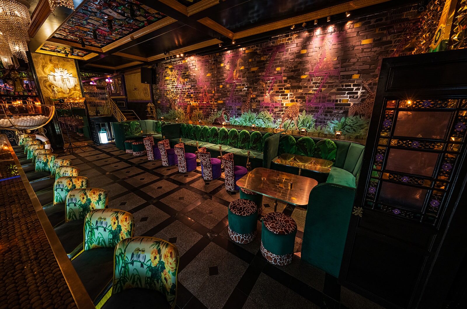 Main floor with giraffe murals, emerald velvet booths and chandelier